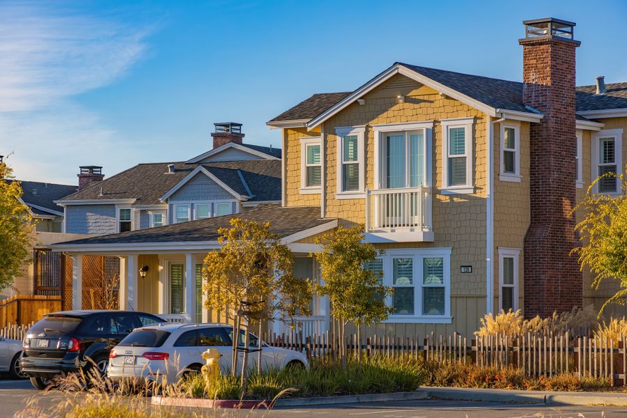 Yellow two-story neighborhood home with a covered front porch